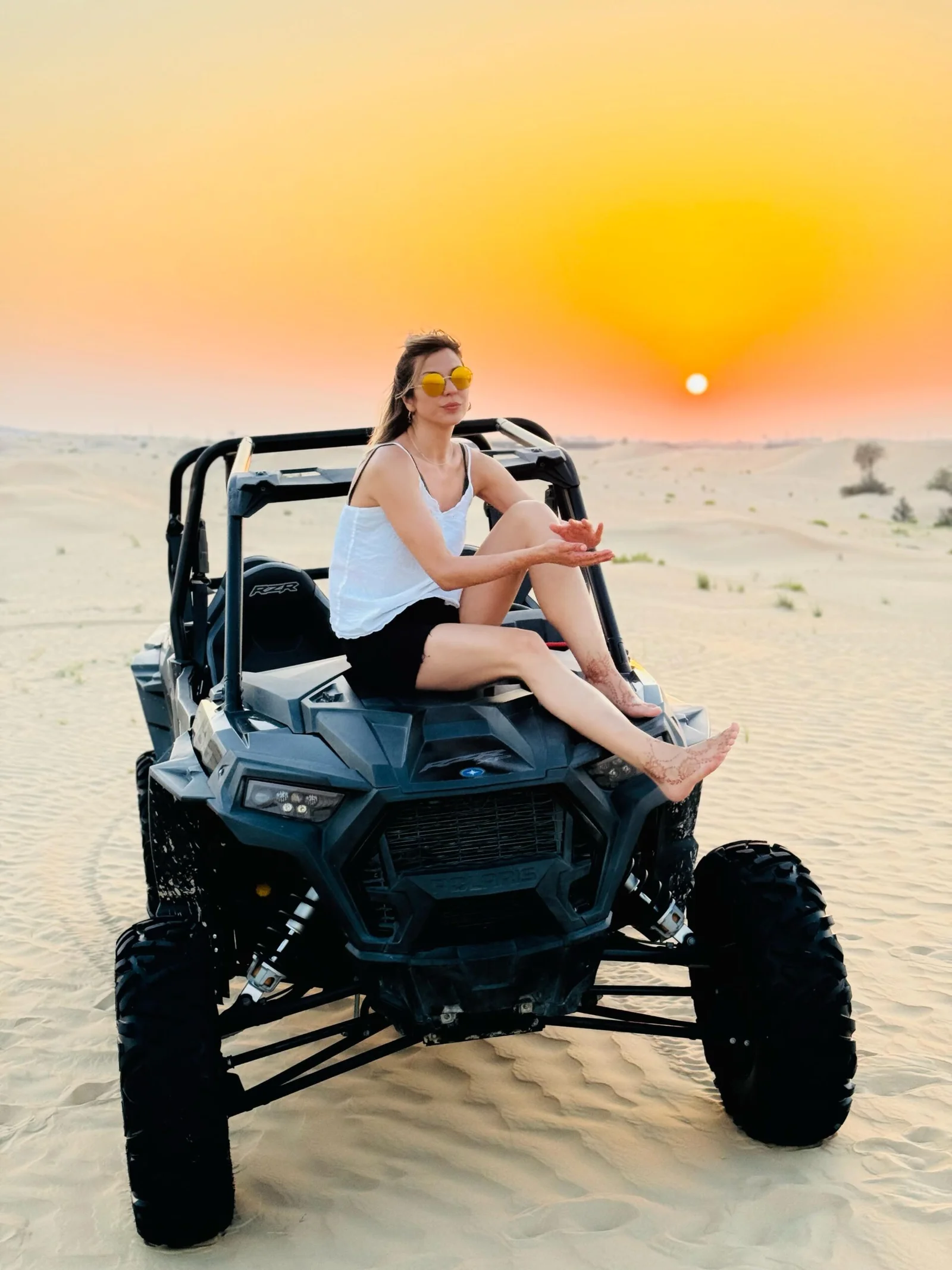 Visitor walking and sandboarding across Abu Dhabi dunes